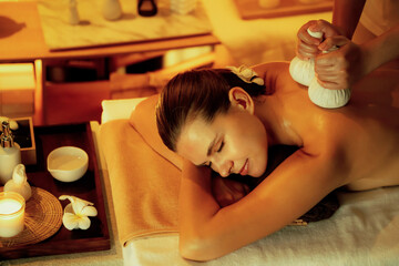 Hot herbal ball spa massage body treatment, masseur gently compresses herb bag on woman body....