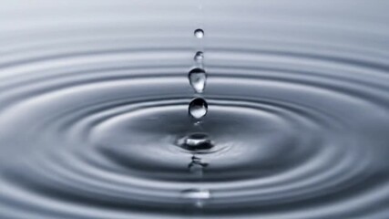 Captivating slow motion video captures a single water droplet falling, creating perfect ripples across a serene surface, embodying purity and calm. - Powered by Adobe