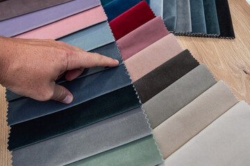 Customer hand picking fabric textile swatch color sample from palette for furniture upholstery choice