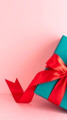 Teal gift box with red ribbon on a pink background