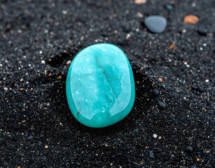 Teal gemstone on black sand