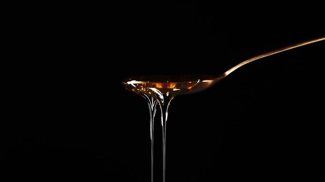 Spoon Full of Honey Against a Black Background Dripping