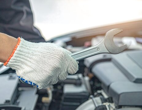Mechanic holding wrench near car engine