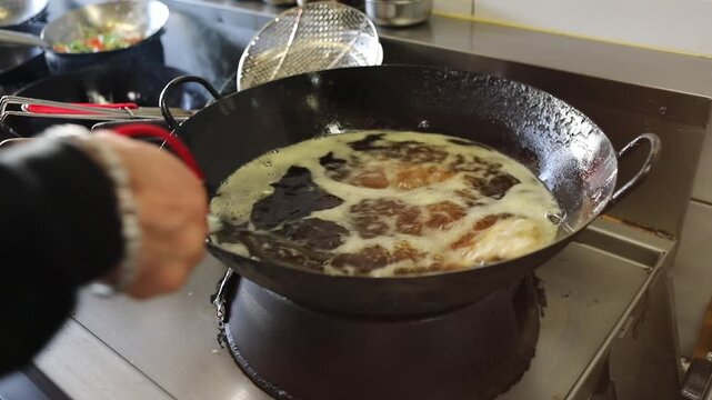 Professional chef frying duck fillet in hot oil with open flame in a pan at bistro kitchen