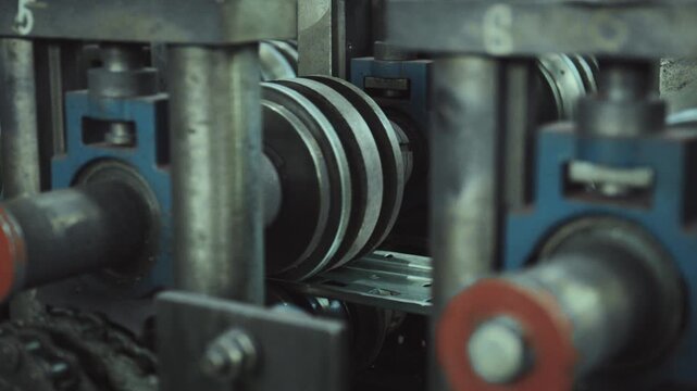 Heavy industry machinery shaping perforated steel profiles on an automated production line in a factory, showing the roll forming process and metalworking manufacturing with precision engineering