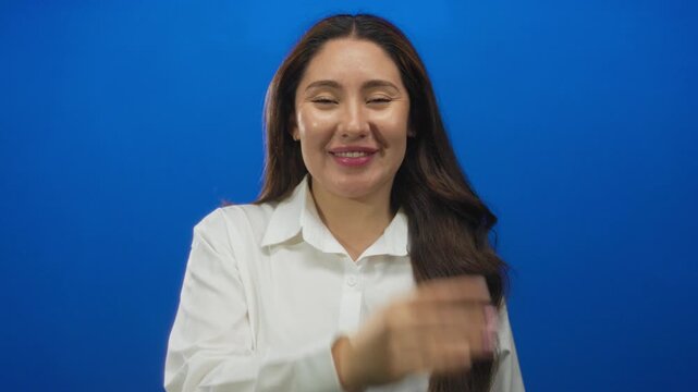 Woman blowing a playful kiss with lips toward camera in a bright blue studio setting; affection connection intimacy.