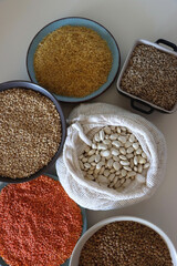 Bowls and bags full of various healthy grains and legumes. Top view.