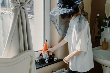 A teenage girl lies with a Halloween gnome on the windowsill in the room.
