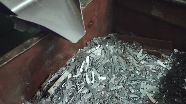 Close up view of steel scrap and metal waste falling from a chute on a conveyor belt, representing industrial recycling, manufacturing processes, and the metallurgy industry production line