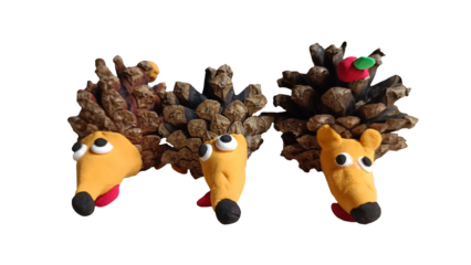 Three handmade hedgehogs from pine cones and clay isolated on white background
