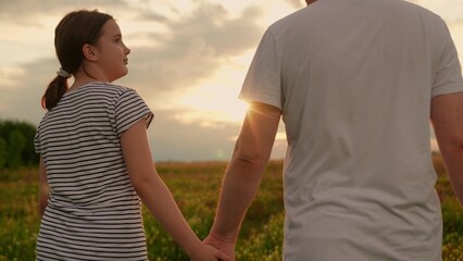 Father daughter walk hand in hand in summer park. Dad daughter stroll together in nature. Happy family in nature. Parents dad daughter celebrate happy childhood. Family picnic travel healthy lifestyle