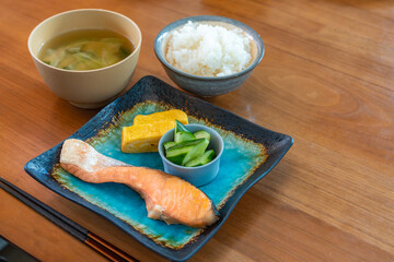 Japanese breakfast with grilled salmon, tamagoyaki, cucumber side dish, rice and miso soup
