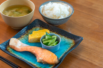 Japanese breakfast with grilled salmon, tamagoyaki, cucumber side dish, rice and miso soup
