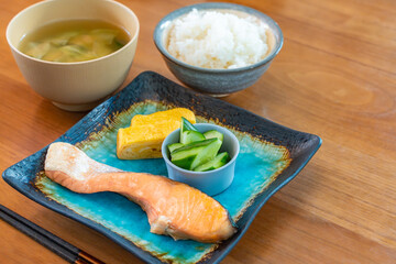 Japanese breakfast with grilled salmon, tamagoyaki, cucumber side dish, rice and miso soup
