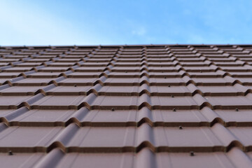 Dark brown metal tile roof against blue sky.  Copy space