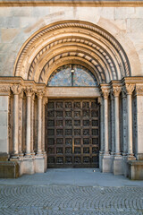 Obraz premium Romanesque stone portal of the Grossmunster church frames a large bronze door with sculpted panels depicting Reformation scenes in Zurich, Switzerland