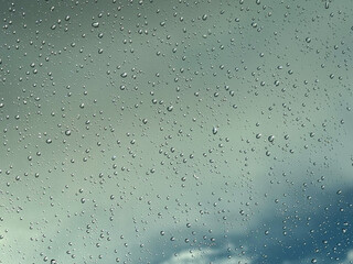 Water drops on car glass, rain drops on clear window. Raindrops falling on the glass of the car. Suitable for use in abstract backgrounds. Raindrops on the car window against the background of a sky. 
