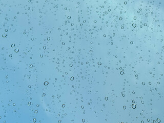 Water drops on car glass, rain drops on clear window. Raindrops falling on the glass of the car. Suitable for use in abstract backgrounds. Raindrops on the car window against the background of a sky. 