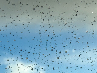 Water drops on car glass, rain drops on clear window. Raindrops falling on the glass of the car. Suitable for use in abstract backgrounds. Raindrops on the car window against the background of a sky. 
