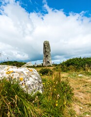 Stone monument on a grassy hill under a partly cloudy sky