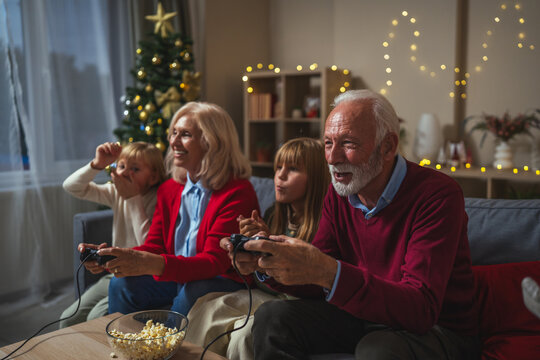 Grandparents and grandchildren playing video game feeling excited