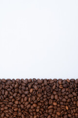 A close up of coffee beans on a white background. The beans are scattered in a way that they create a border around the white background. Concept of warmth and comfort