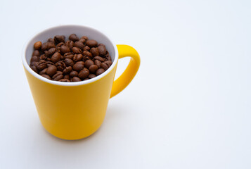 A yellow coffee mug filled with coffee beans. The coffee beans are scattered throughout the cup, creating a cozy and inviting atmosphere