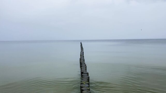 View of the Baltic Sea with wooden groynes, calm sea with small waves