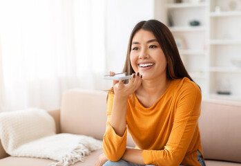Voice application. Happy young asian woman hold mobile phone talk using digital voice recorder dictate voicemail audio message, enjoy tech innovation search data at web via mobile ai assistant