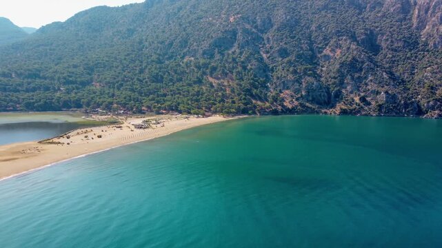 aerial drone shot captures the pristine golden sands of Iztuzu Beach in Dalyan, Turkey, famously known as Turtle Beach. This unique natural wonder is a narrow spit of land separating the freshwater Da