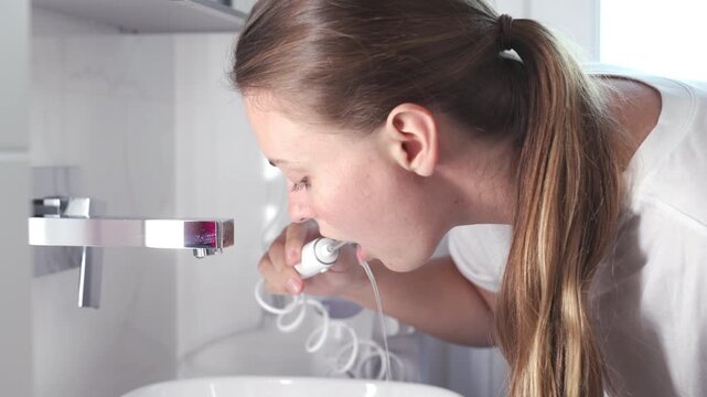 Close-up of a woman using a water flosser during oral care. Concept: effective dental hygiene and modern self-care.