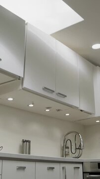 Modern kitchen interior showcasing sleek white cabinets, stainless steel appliances, recessed lighting, and a bright skylight illuminating the clean, minimalist design of the contemporary space