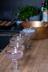 Elegant cocktails served in crystal glasses on a wooden bar, surrounded by ice and greenery, creating a mysterious and inviting atmosphere for a party