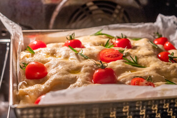 Freshly baked focaccia bread topped with cherry tomatoes and rosemary, showcasing a golden crust and fluffy texture, perfect for traditional Italian cuisine and culinary delights