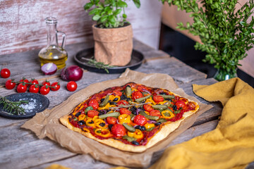 Focaccia bread topped with cherry tomatoes, rosemary, and colorful peppers, beautifully arranged on...