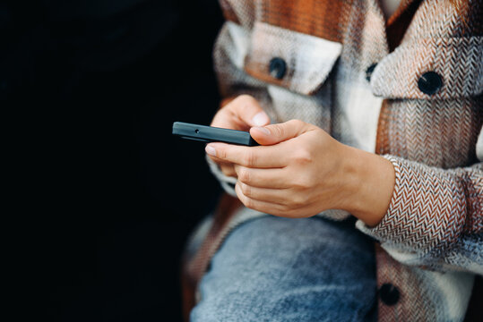 young woman holds smartphone in hands, sitting in car, travel blogger, close-up view, no face, copy space