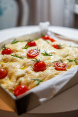Freshly baked focaccia topped with vibrant cherry tomatoes and fragrant rosemary, showcasing a soft, fluffy texture and golden crust, perfect for traditional culinary delights