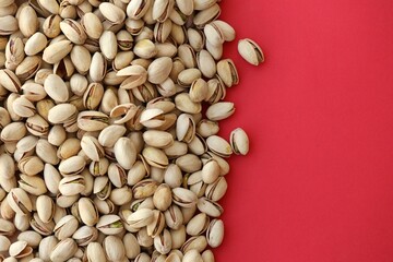 Tasty unpeeled pistachios on bright red background, top view flat lay background pattern