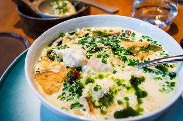 Overhead view of traditional Norwegian fish soup, creamy broth served in a white bowl with fish fillet, bread, and fresh scallions from a Norway local restaurant.