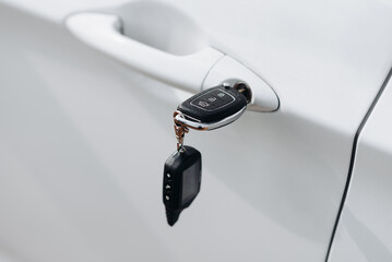 black car keys in car keyhole, close-up view, white car, opening or closing car with signalization or alarm system, car theft, carjacking, car safety concept, selective focus