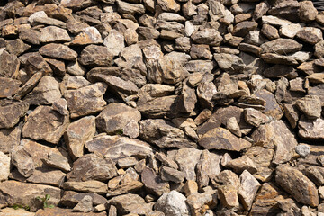 Natural stone wall composed of various sizes and shapes of rocks, showcasing earthy tones and textures, ideal for backgrounds or landscaping design projects