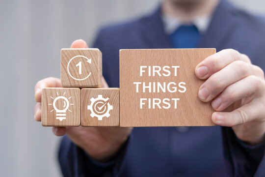 Business concept of first things first. Person holding wooden blocks with icons sees the inscription FIRST THINGS FIRST.