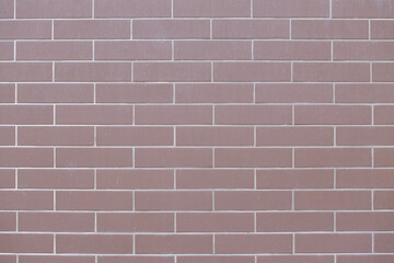 Fototapeta premium Textured brown brick wall with uniform rectangular tiles, showcasing a modern architectural design, ideal for backgrounds or construction-related projects