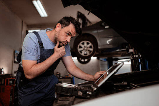 Mechanic analyzing vehicle data in garage during afternoon service