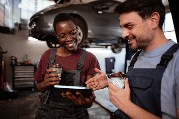 Mechanics discussing work over coffee in an auto repair shop during the day