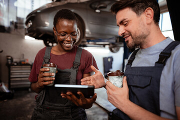 Mechanics discussing car repair while enjoying coffee in a garage setting