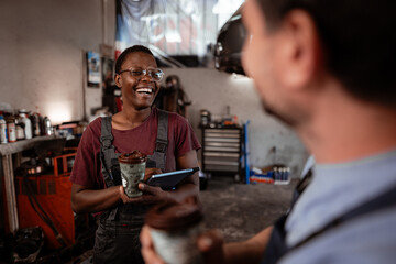 Friendly conversation in a busy auto repair shop during the afternoon shift