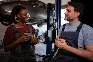 Mechanics discuss car repairs while enjoying snacks in a busy workshop