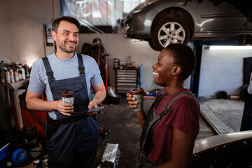 Mechanics enjoying coffee break in garage while discussing car repairs