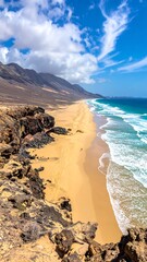High-angle view of a sandy beach, ocean waves, and mountains